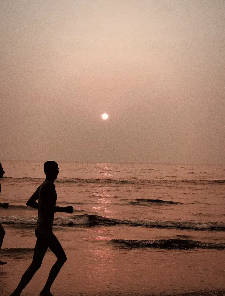 A runner on the shore at dawn
